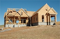 Image of a house in progress with a wooden roof being constructed.