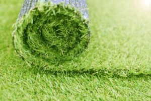 A roll of artificial grass is positioned on the ground awaiting use or transport