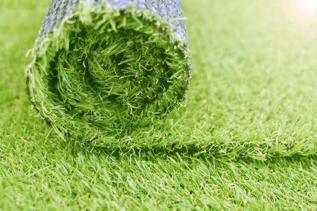 A roll of artificial grass is positioned on the ground awaiting use or transport