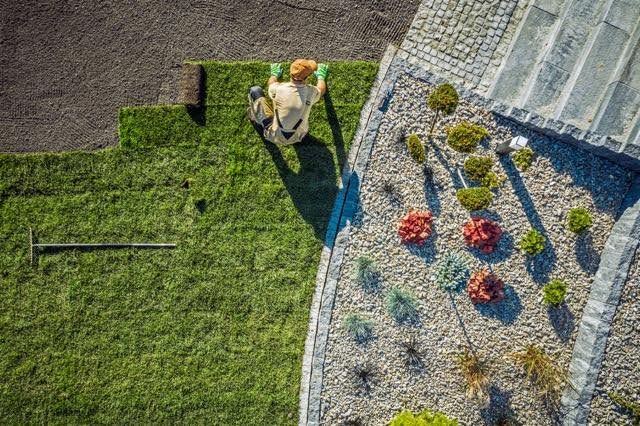 Overhead shot of a man tending to a lawn using a mower amidst a lush green landscape