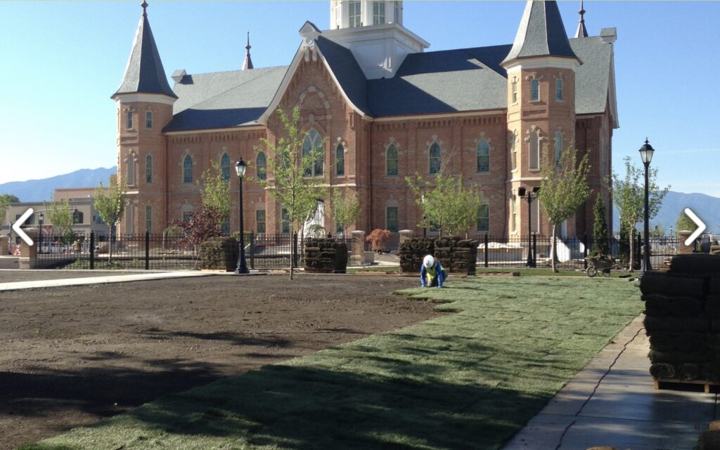Worker install sod for new lawn landscape project in front of building with fresh grass rolls being laid