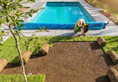 A man tends to a lawn near a pool, showcasing lush grass from Monarch Sod. A man tends to a lawn near a pool, showcasing lush grass from Monarch Sod.